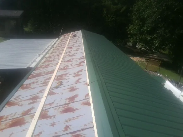 Old rusted panels beside newly installed green metal roofing — Wind Damage Roof Repair by Roofing Brothers in Shabbona