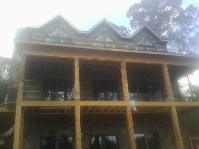 Dormers and porch framing on a large log home under construction — Roof Coating work by our crew in Shabbona
