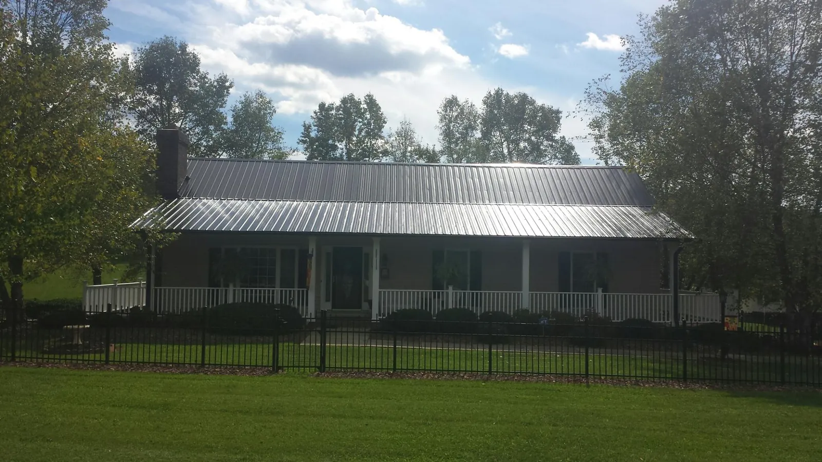 Gray metal roof on a brick ranch with a full width front porch — Gutter Guard Installation work by our crew in Shabbona