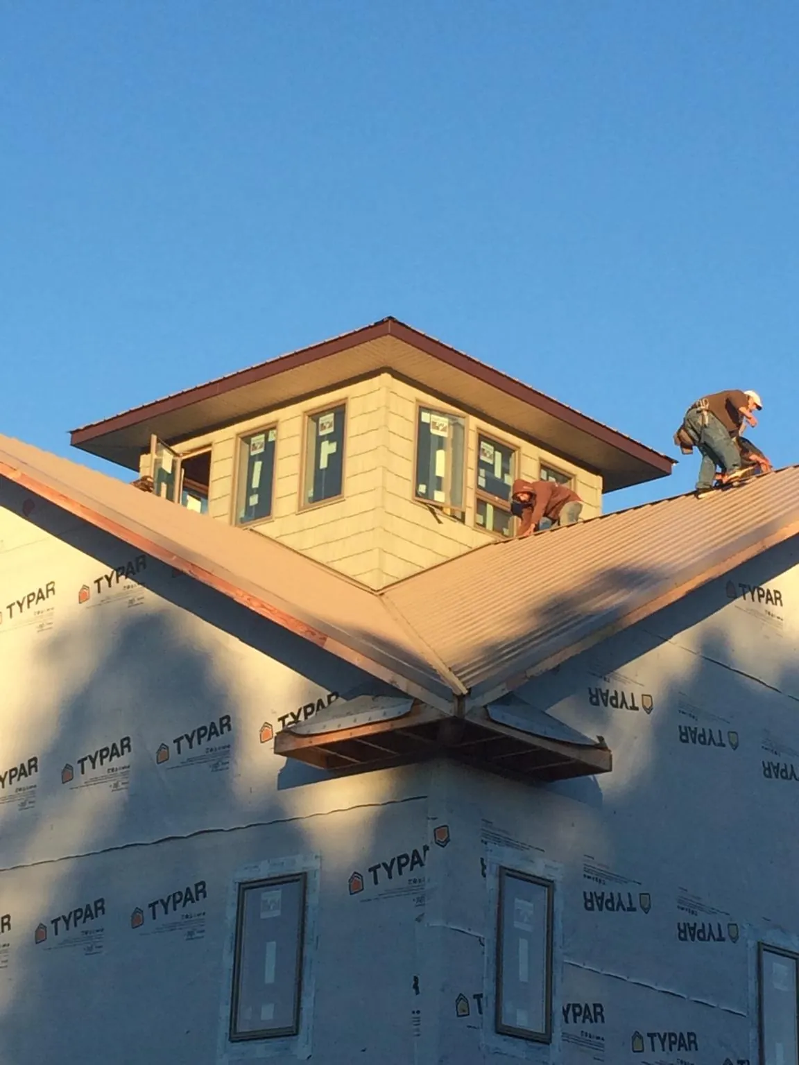Roofers working around a rooftop cupola on a new metal roof at sunset — Roof Waterproofing in Shabbona by Roofing Brothers